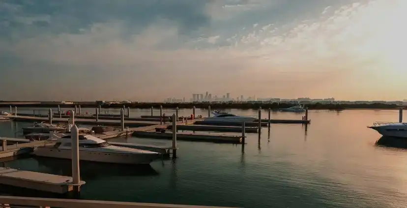 Marina at dusk with moored boats and the Abu Dhabi skyline in the distance