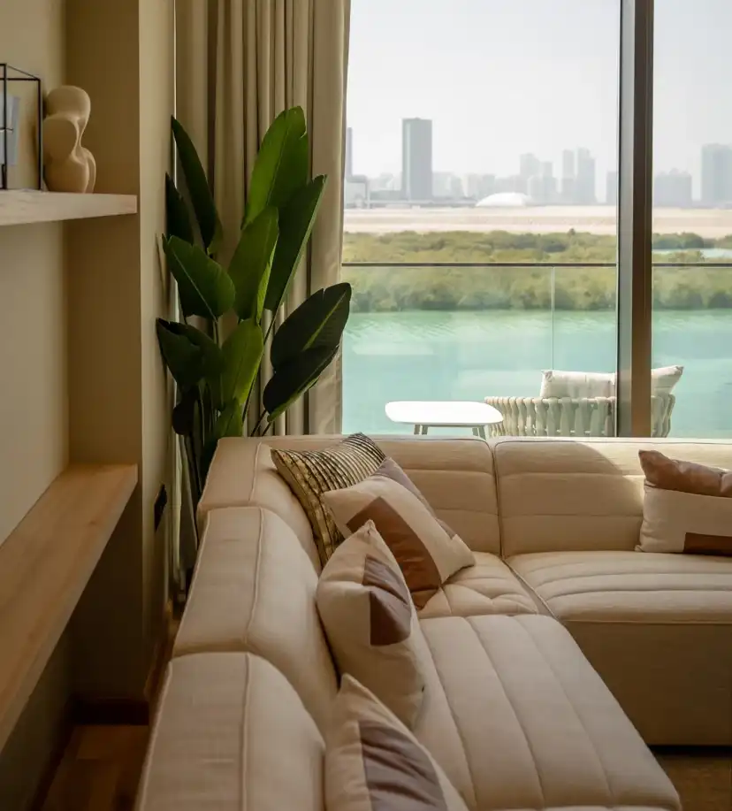 Living room corner with a cream sectional sofa and a window over the water