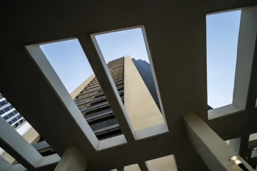 View upward through concrete frames to the glass facade of the tower