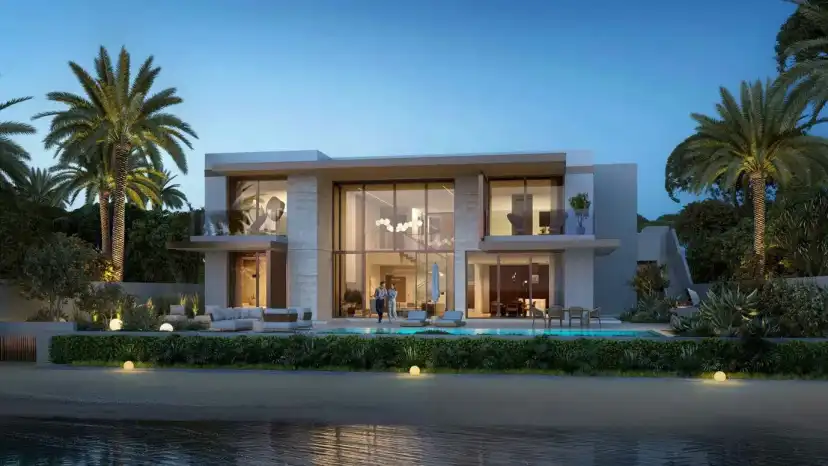 Villa with palm trees and a pool beside the water at dusk