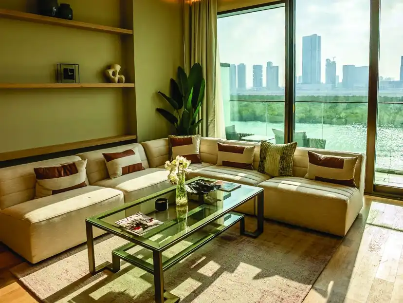 Living area with a sectional sofa, a glass coffee table and a window over the mangroves