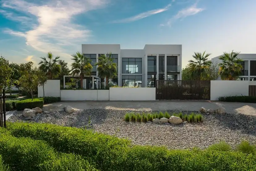 White villa with a timber gate and a gravel garden