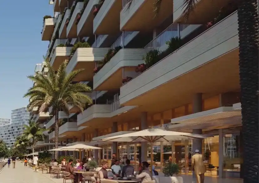 Waterfront promenade with cafes and shaded terraces beneath a marina residential building