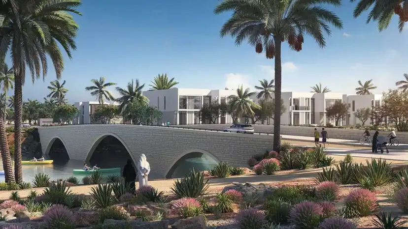Stone arched bridge over the water channel with palm trees and villas beyond