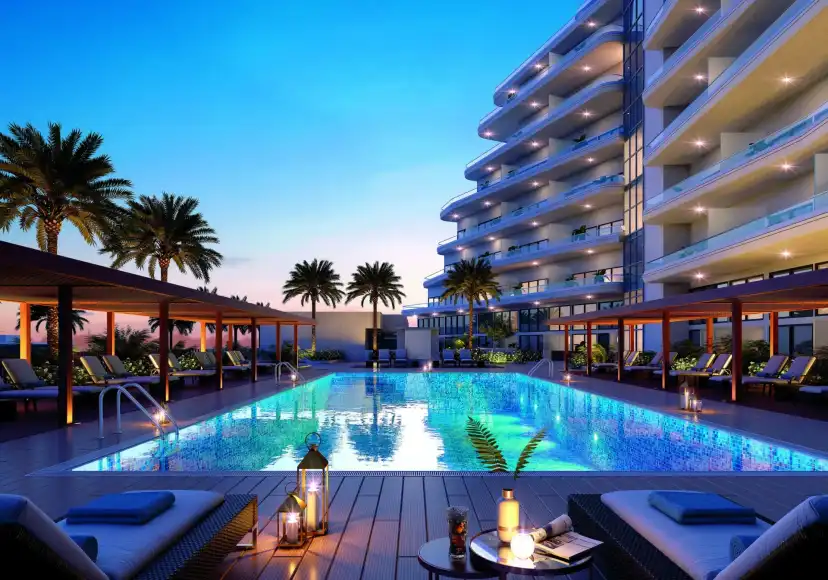 Pool with loungers and cabanas at dusk in front of the Mayyas building